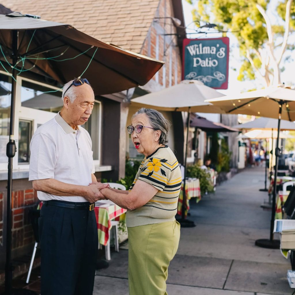 A senior couple holding hands while visiting a town.