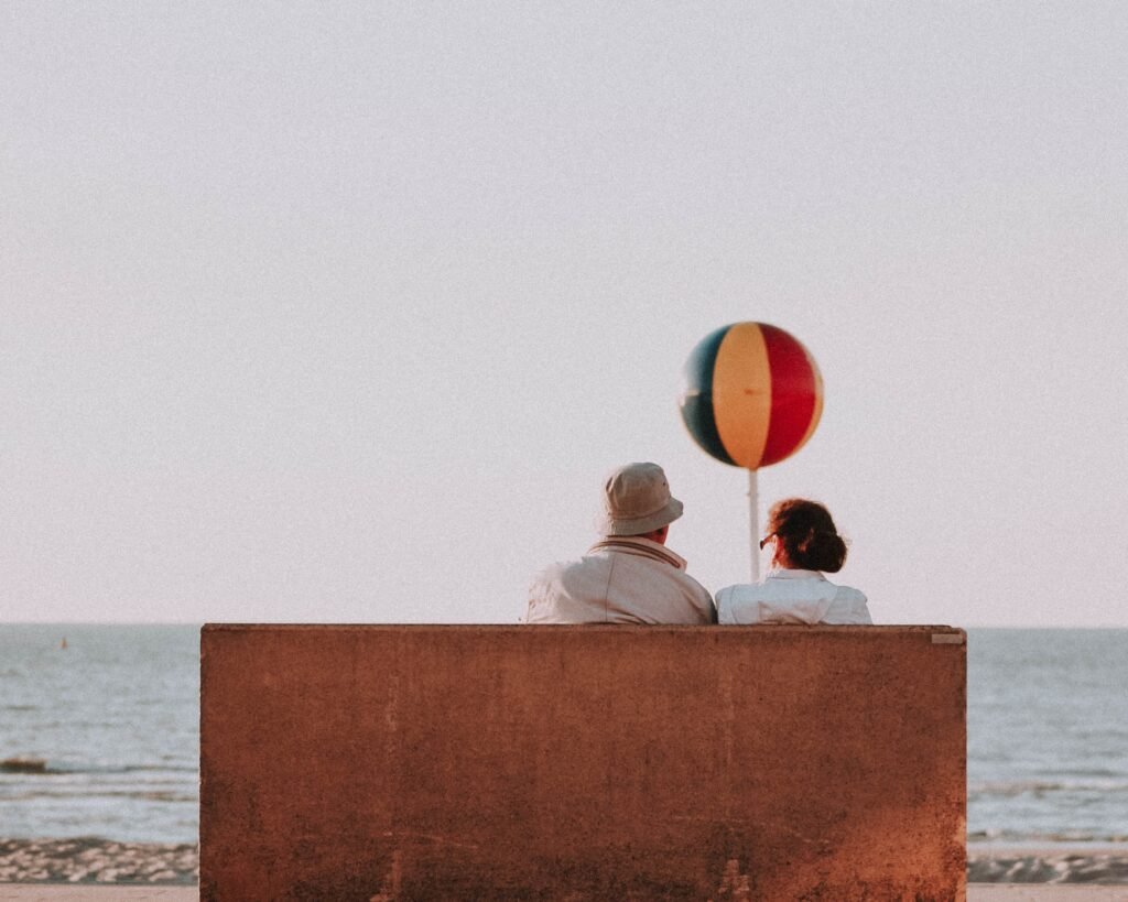 A senior couple sitting on a bench while enjoying a view during their visit in Greece.