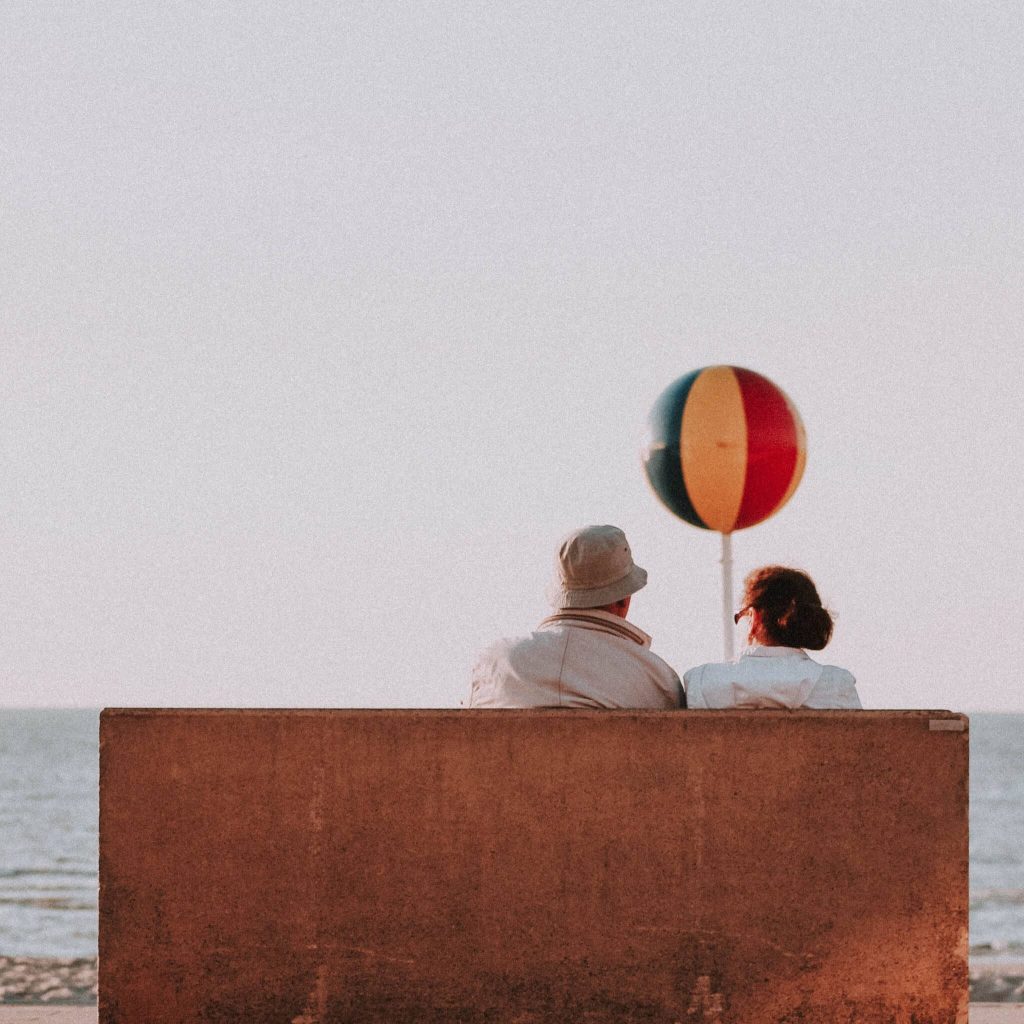 A senior couple sitting on a bench while enjoying a view during their visit in Greece.