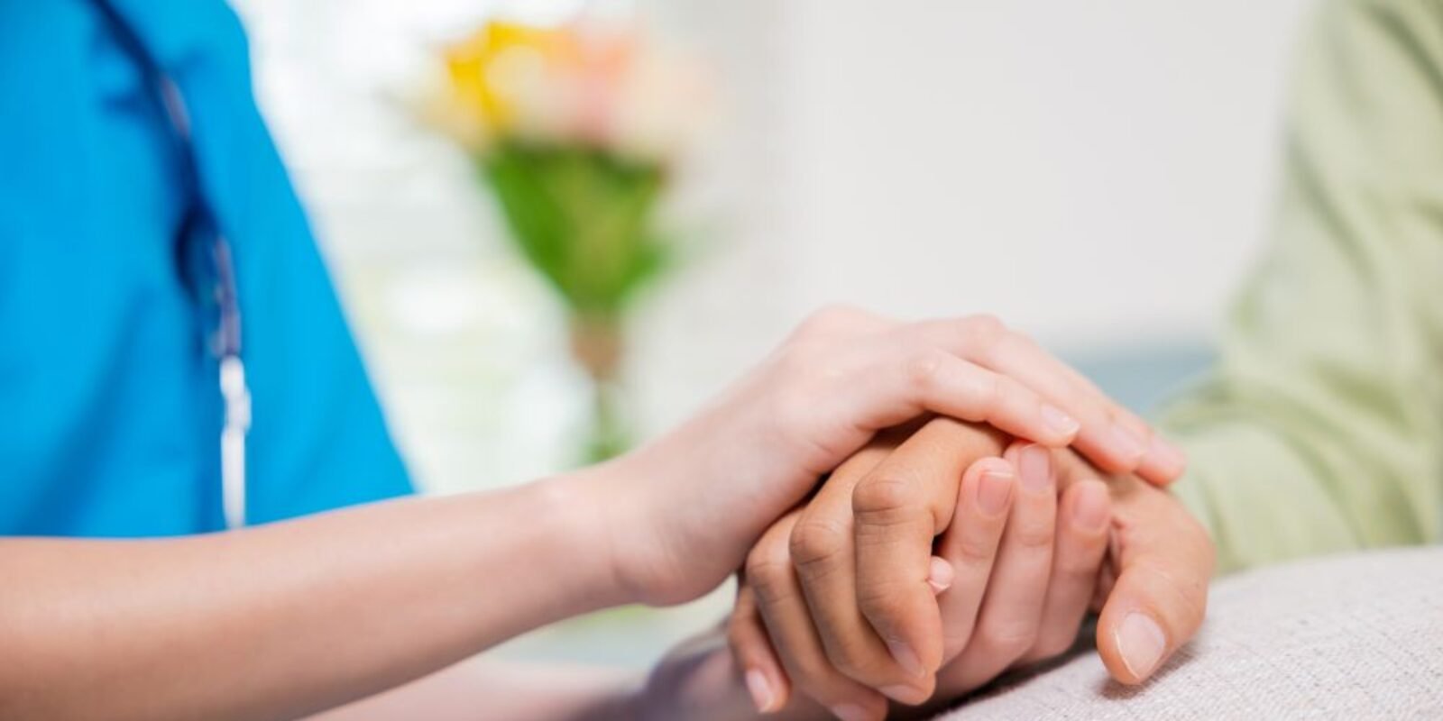 An image of a nurse holding a retirees hand for an article about aged care reform 2025.