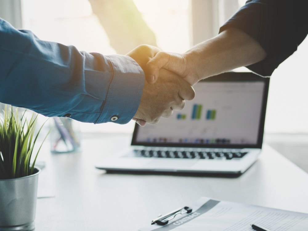 An image of a senior shaking hands with their successor. 