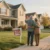 A mid-60's couple waving goodbye to the family home as they prepare for their new, downsized life.
