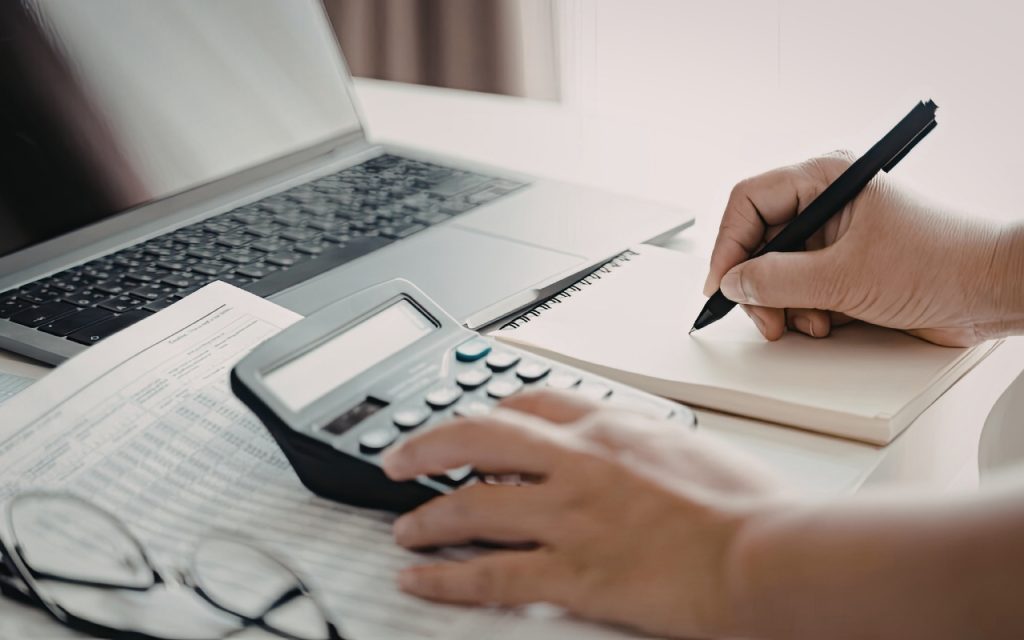 An image of a senior working on a calculator and a piece of paper.